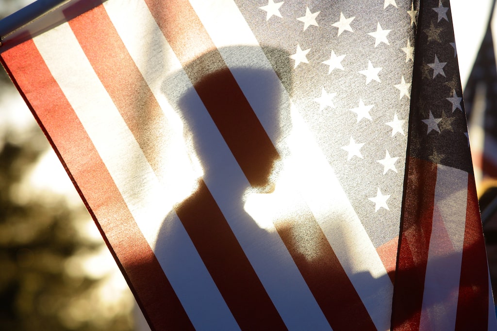 A soldier hiding behind an American flag