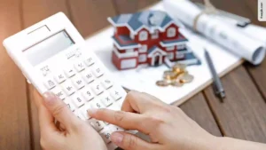 Female hand operating calculator in front of villa house model. FHA Loan Missouri application.