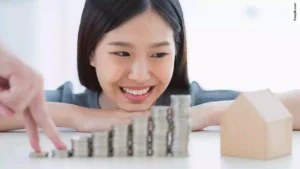 Happy Asian woman hand with coin stack. Applying for a FHA Refinance.